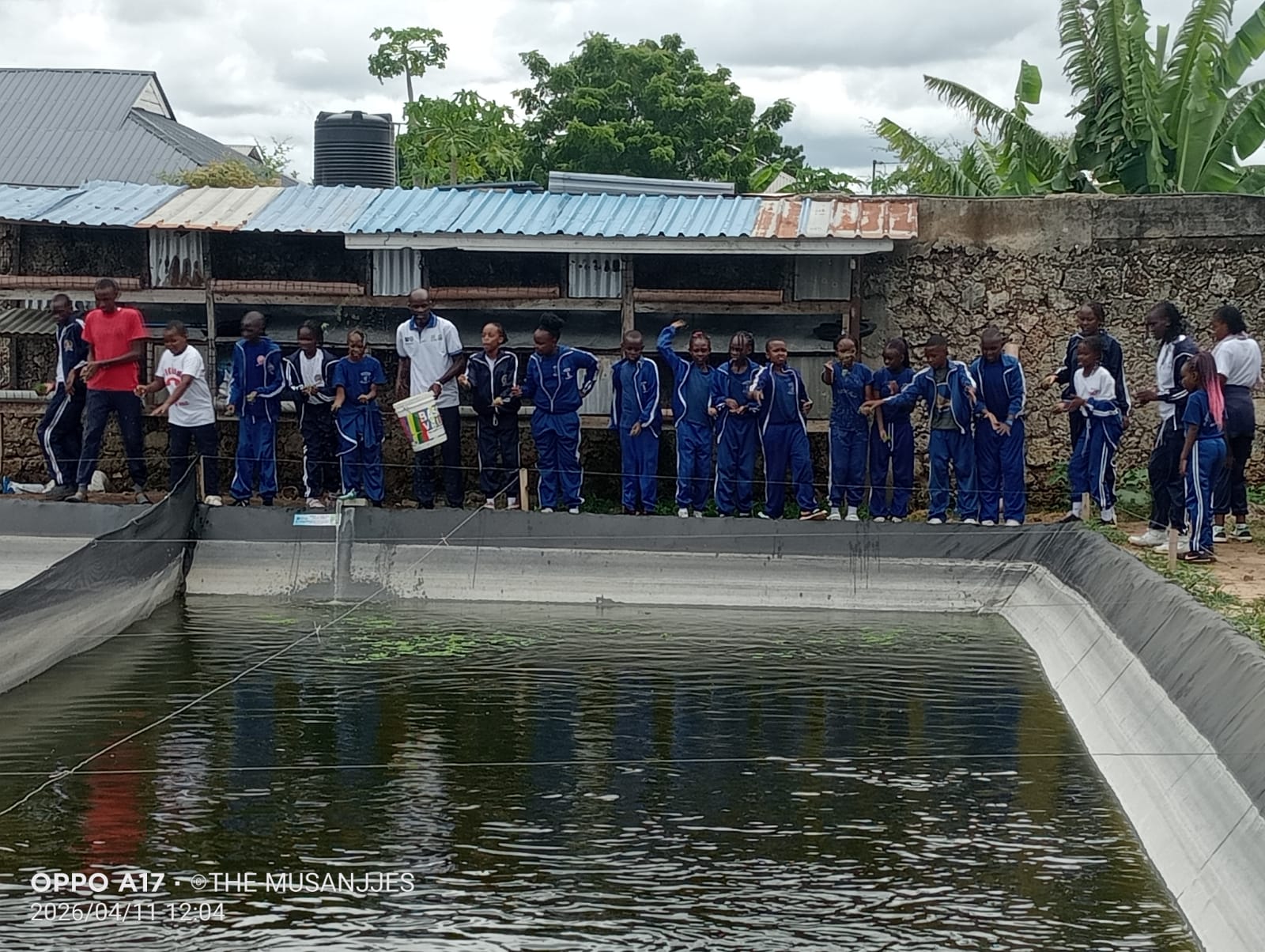Students lined up along a PHYG fish pond during a school visit